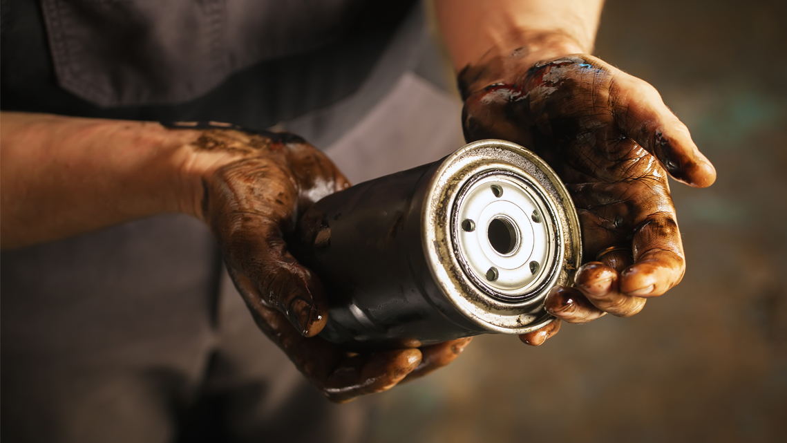 hands holding used oil filter